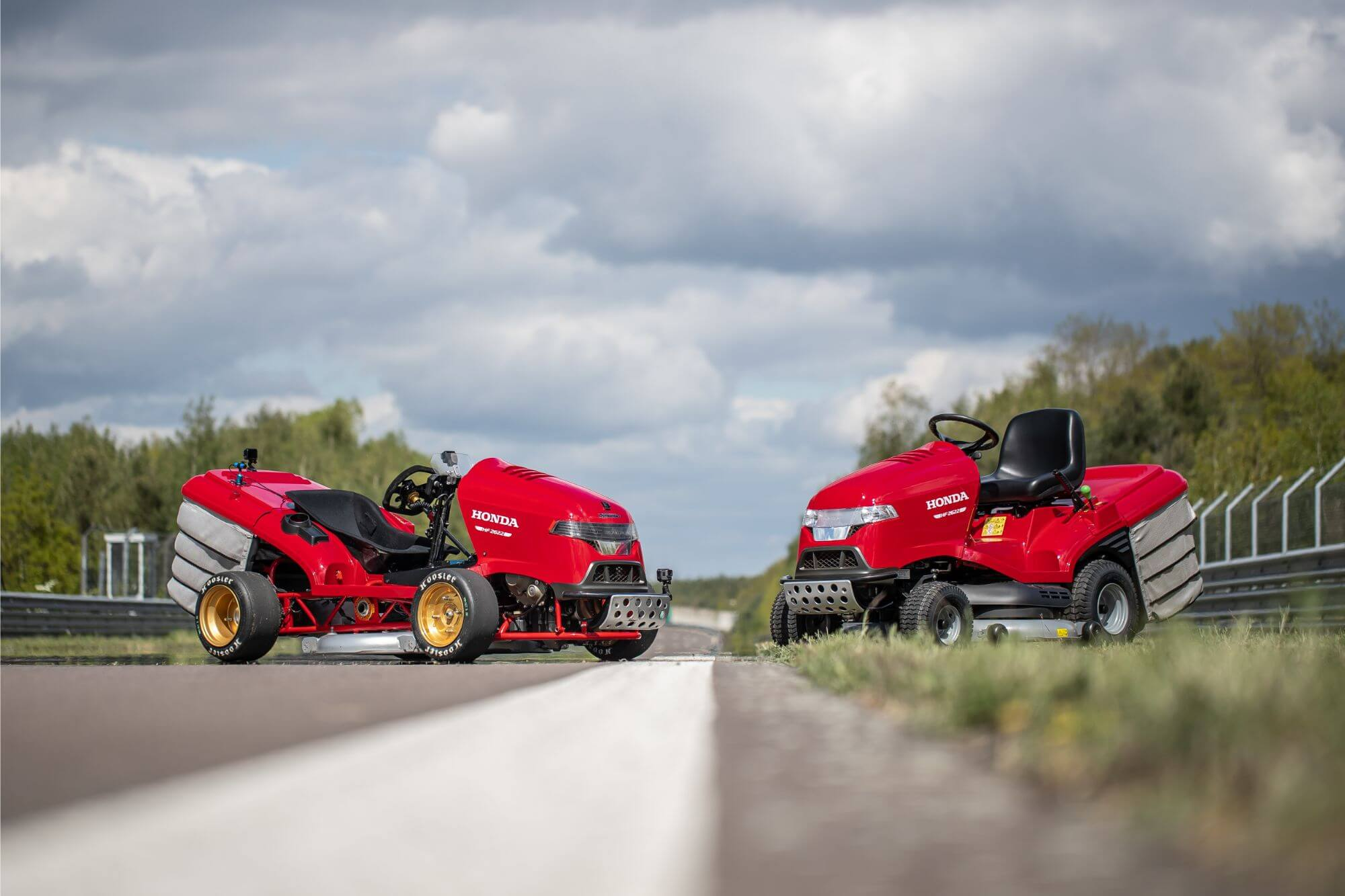Honda Mean Mower V2 next to a standard red Honda lawn mower on a race track, highlighting the performance contrast.