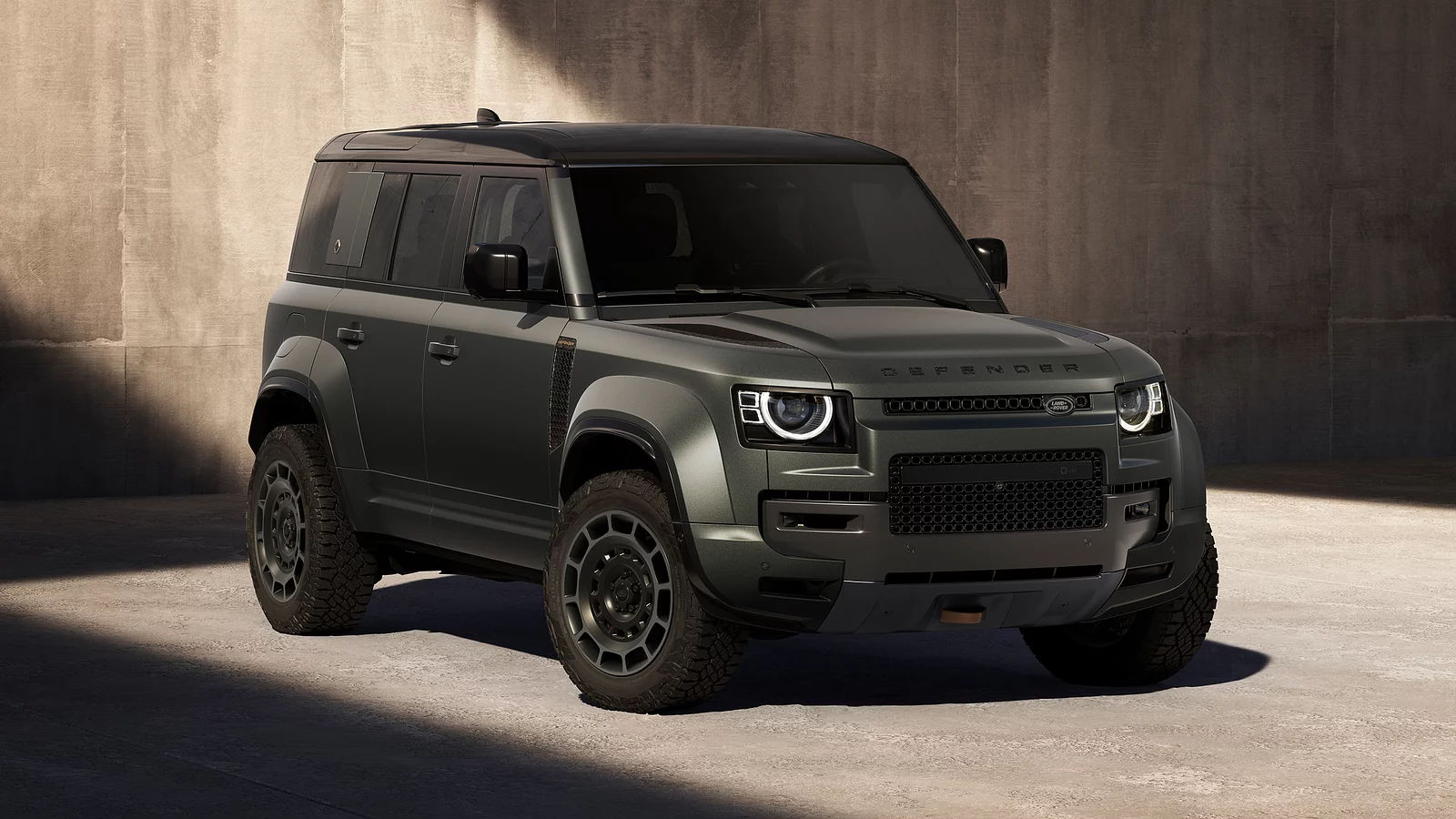 The New Defender OCTA in matte green with rugged tires and modern LED headlights, parked in a sunlit urban environment.